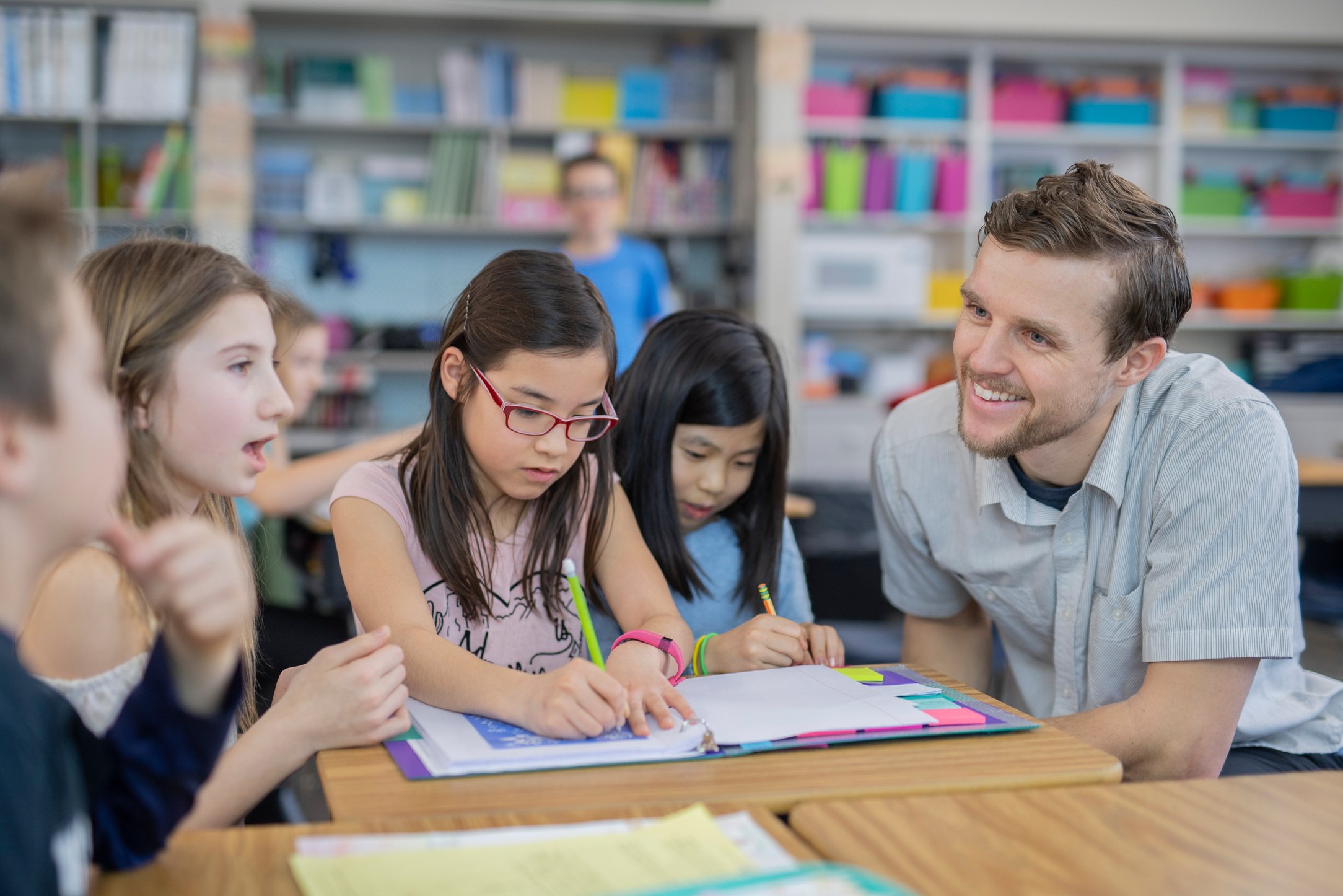 Male teacher helping several of his 4th grade students