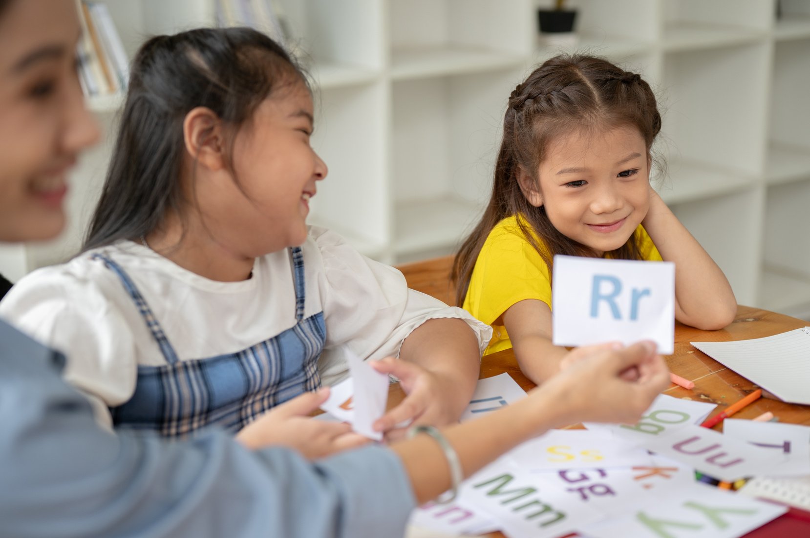 Cheerful Young Asian Girls Studying English Alphabet Flashcards